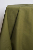 Tissu coton déperlant vert kaki drapé sur un support architectural blanc, formant un pli triangulaire net caractéristique du tissu tenu.
