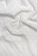 Tissu Le Coton Indien Tissé 002 écru drapé en plis souples, laissant deviner le motif géométrique tissé en relief à contre-jour.