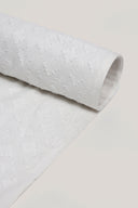 Tissu Le Coton Indien Tissé 002 écru enroulé en rouleau, motif géométrique tissé en relief visible sur toute la longueur.