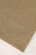 Gros plan sur le coin du tissu La Rayure 001 kaki à fines rayures écru, mettant en valeur le motif et la lisière effilochée.