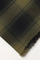 Tissu Le Carreau 004 kaki et anthracite à carreaux façon tartan ombré, enroulé en rouleau laissant voir la lisière tissée.
