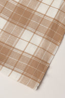 Tissu Le Carreau 008 écru à carreaux caramel façon vichy, enroulé en rouleau laissant voir la lisière tissée.