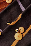 Tissu Misty noir avec des boutons moutarde et un bouton bicolore noir et doré posés sur le motif graphique.