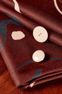Tissu Misty bordeaux avec deux boutons ivoire posés sur le motif graphique.
