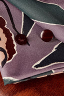 Tissu Peony lavande plié avec deux boutons bordeaux posés sur le motif floral.