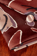 Tissu Peony terracotta plié avec un bouton nacré rose posé sur le motif floral.