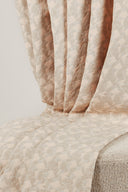 Gros plan sur les plis du tissu jacquard rose poudré laissant apparaître le motif géométrique et l'éclat lurex.