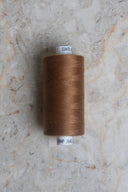 Cône de fil pour surjeteuse Havana Brown marron caramel posé sur une pierre claire – Atelier Brunette