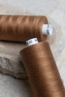 Gros plan sur deux bobines de fil pour surjeteuse Havana Brown et leur étiquette de référence – Atelier Brunette