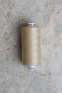 Cône de fil pour surjeteuse Limestone beige sable posé sur une pierre claire – Atelier Brunette