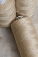 Gros plan sur des bobines de fil pour surjeteuse Limestone beige sable empilées – Atelier Brunette