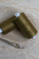 Deux bobines de fil pour surjeteuse Noble Green vert olive posées sur une pierre naturelle – Atelier Brunette