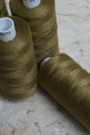 Gros plan sur des bobines de fil pour surjeteuse Noble Green vert olive empilées – Atelier Brunette