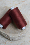 Deux bobines de fil pour surjeteuse Velvet Syrah rouge bordeaux posées sur une pierre naturelle – Atelier Brunette