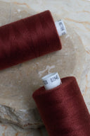 Gros plan sur deux bobines de fil pour surjeteuse Velvet Syrah et leur étiquette de référence – Atelier Brunette