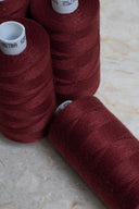 Gros plan sur des bobines de fil pour surjeteuse Velvet Syrah rouge bordeaux empilées – Atelier Brunette
