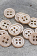 Close-up of the same small round four-hole buttons, highlighting the shine of the material.