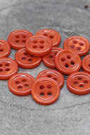 Close-up of the same small four-hole round buttons, highlighting the shine of the material.