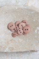 Top-down view of the buttons, stacked at the centre of a marbled beige stone.
