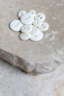 Les boutons vus de dessus, empilés au centre d'une pierre beige marbrée.