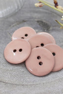 Close-up of the same glossy enamel buttons, revealing the smooth texture and shine of the material.