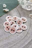 Close-up of the same enameled buttons rimmed with pearl, revealing the glossy texture and white trim.