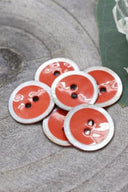 Close-up of the same enameled buttons rimmed with pearl, revealing the glossy texture and white trim.
