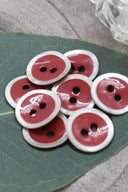 Close-up of the same enameled buttons rimmed with pearl, revealing the glossy texture and white trim.