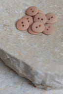 Top-down view of the buttons, stacked at the centre of a marbled beige stone.