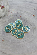 Close-up of the same round buttons rimmed with a gold trim, highlighting the shine of the enamel.