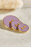 Close-up of the same round buttons rimmed with a gold trim, highlighting the shine of the enamel.