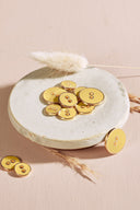 Close-up of the same round buttons rimmed with a gold trim, highlighting the shine of the enamel.