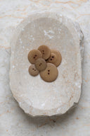 Les boutons vus de dessus, empilés au centre d'une pierre beige marbrée.