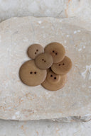 Autre vue rapprochée des boutons sur la pierre beige marbrée, sous un angle différent.