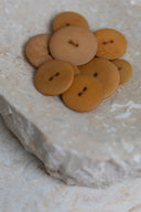Les boutons vus de dessus, empilés au centre d'une pierre beige marbrée.