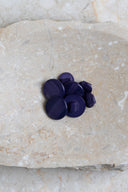 Boutons ronds bombés à queue, sans trous apparents, finition nacrée bleu marine cobalt, présentés en tas de tailles variées sur une dalle de pierre beige marbrée.