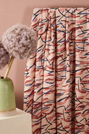 Fuji fabric in powder pink draped in loose folds on a white stand, styled in a pink and plum setting.