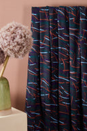 Fuji fabric in anthracite draped in loose folds on a white stand, styled in a pink and plum setting.