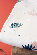 Palmetto fabric in ivory folded into several layers, revealing the palm-leaf pattern in navy and powder pink, near dried twigs.