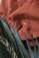 Sunset fabric in terracotta draped with dried wheat stalks placed on top, highlighting the lightness of the gauze.