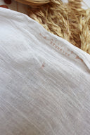 Tissu Sunset écru drapé, laissant apparaître un marquage imprimé « ATELIER BRUNETTE » sur la trame légère du tissu.