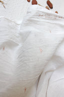 Pli du tissu Sunset écru en gaze transparente, motifs soleil terracotta répartis sur toute la surface.