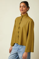 Amirale Shirt pattern – Woman, side view, khaki loose-fitting shirt worn with jeans, beige background – Atelier Brunette