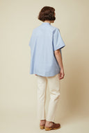 Patron Chemisette Structurée – vue de dos, coloris bleu ciel portée avec pantalon blanc – Atelier Brunette