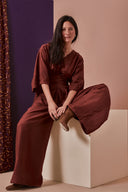 Patron La Combi Addie – Femme assise, combinaison bordeaux manches kimono, ceinture nouée, fond violet – Atelier Brunette