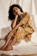 Patron La Robe Tunique – Femme assise, robe tunique imprimée géométrique terracotta/or, fond tissu crème – Atelier Brunette
