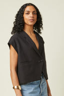 Patron Veste Spencer – vue de face, veste spencer noire, col tailleur croisé, mancheron, fond beige – Atelier Brunette