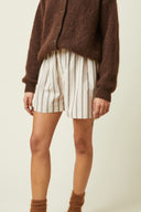 Patron LE Boxer – Model en pied, boxer rayé beige blanc, cardigan marron foncé, fond beige – Atelier Brunette