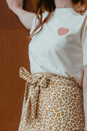 Hack La Jupe – Détail ceinture nouée, jupe léopard camel taille haute, t-shirt écru cœur rose, fond marron – Atelier Brunette