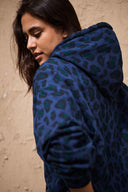 Patron Le Hoodie – Femme penchée, hoodie oversize léopard bleu marine avec capuche, fond mur pierre – Atelier Brunette